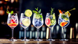 Fototapeta Kuchnia - Five colorful gin tonic cocktails in wine glasses on bar counter in pup or restaurant.