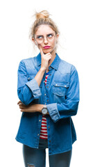 Canvas Print - Young beautiful blonde woman wearing glasses over isolated background with hand on chin thinking about question, pensive expression. Smiling with thoughtful face. Doubt concept.