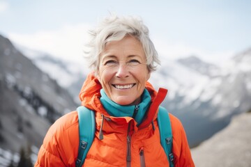 Wall Mural - Portrait of a grinning woman in her 60s sporting a breathable hiking shirt in front of pristine snowy mountain