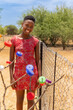 black teenager in the village township in south africa, standing in the yard next to the mesh fence, trees with caps in the foreground