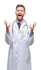 Sticker - Young handsome doctor man over isolated background crazy and mad shouting and yelling with aggressive expression and arms raised. Frustration concept.