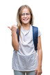 © Krakenimages.com - Young beautiful smart student girl wearing backpack over isolated background smiling with happy face looking and pointing to the side with thumb up.