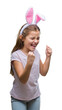 © Krakenimages.com - Young beautiful girl wearing easter bunny ears over isolated background very happy and excited doing winner gesture with arms raised, smiling and screaming for success. Celebration concept.