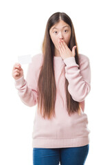 Poster - Young Chinese woman over isolated background holding visit card cover mouth with hand shocked with shame for mistake, expression of fear, scared in silence, secret concept