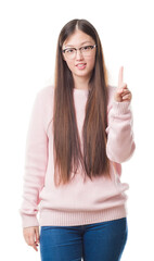 Canvas Print - Young Chinese woman over isolated background wearing glasses showing and pointing up with finger number one while smiling confident and happy.