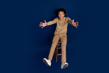 Poster - Full size photo of nice young man sit chair falling back wear trendy beige outfit isolated on dark blue color background