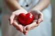 Healthcare worker shows compassion while holding red heart symbol in blurred background, symbolizing cardiology and overall wellness