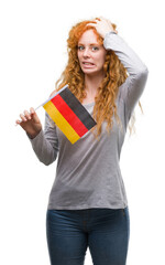 Poster - Young redhead woman holding flag of Germany stressed with hand on head, shocked with shame and surprise face, angry and frustrated. Fear and upset for mistake.