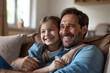 © Volodymyr - A happy father in his 30s sits with his daughter at home, watching an interesting video on a kids' channel online. They share a moment of joy and connection as they enjoy their leisure time together.