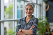 © Volodymyr - A smiling, happy, and confident Indian old mature professional business woman, a corporate leader and senior middle-aged female executive, stands in her office with arms crossed, projecting confidence