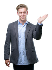 Wall Mural - Young handsome blond business man smiling cheerful presenting and pointing with palm of hand looking at the camera.