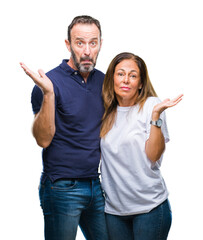 Wall Mural - Middle age hispanic casual couple over isolated background clueless and confused expression with arms and hands raised. Doubt concept.