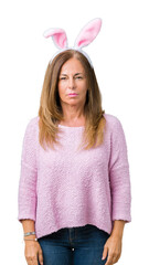 Wall Mural - middle age brunette woman wearing easter rabbit ears over isolated background with serious expressio
