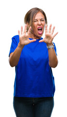 Wall Mural - Middle age senior hispanic woman over isolated background afraid and terrified with fear expression stop gesture with hands, shouting in shock. Panic concept.