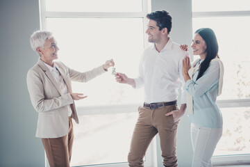 Poster - Photo of lady realtor give new apartment key young married couple white interior indoors