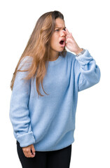 Poster - Young beautiful brunette woman wearing blue winter sweater over isolated background shouting and screaming loud to side with hand on mouth. Communication concept.