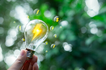 Wall Mural - Hand holding light bulb ideas on a background. Together with the conservation of alternative energy and alternative energy. Clean energy business.