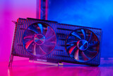 Fototapeta  - Powerful modern GPU Video Card with two fans with PC case on background in neon light. Rendering and gaming computer hardware components.