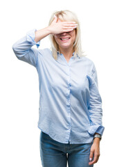 Wall Mural - Young beautiful blonde business woman wearing glasses over isolated background smiling and laughing with hand on face covering eyes for surprise. Blind concept.