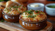 Close up of french onion soups in brown pots on wooden board, home or cosy cafe setting.