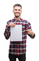 Wall Mural - Young hipster adult man holding blank paper sheet very happy pointing with hand and finger