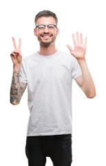 Sticker - Young tattooed adult man showing and pointing up with fingers number seven while smiling confident and happy.