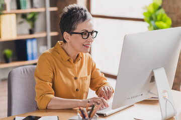 Wall Mural - Photo of nice senior woman computer sit table dressed yellow formalwear executive business leader work in cozy beautiful office interior