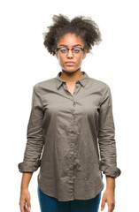 Wall Mural - Young afro american woman wearing glasses over isolated background with serious expression on face. Simple and natural looking at the camera.