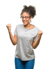 Wall Mural - Young afro american woman wearing glasses over isolated background very happy and excited doing winner gesture with arms raised, smiling and screaming for success. Celebration concept.