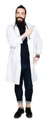 Wall Mural - Doctor with long hair wearing medical coat and stethoscope cheerful with a smile of face pointing with hand and finger up to the side with happy and natural expression on face