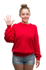 Wall Mural - Young blonde woman wearing bun and red sweater showing and pointing up with fingers number five while smiling confident and happy.