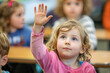 School child raising hand ready to answer a question on the classroom. Back to school concept.