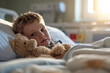 Sick child lying in bed in a hospital with his favorite stuffed toy. Ill kid hospitalized in pediatric clinic