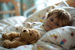 Sick child lying in bed in a hospital with his favorite stuffed toy. Ill kid hospitalized in pediatric clinic