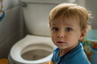 Adorable toddler near the flush toilet in bathroom. Potty training and hygiene concept.