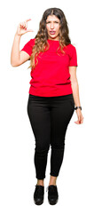 Poster - Young beautiful woman wearing casual t-shirt smiling and confident gesturing with hand doing size sign with fingers while looking and the camera. Measure concept.