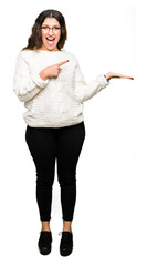 Sticker - Young beautiful woman wearing glasses amazed and smiling to the camera while presenting with hand and pointing with finger.