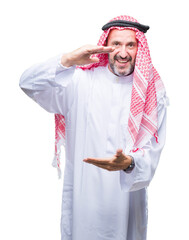 Wall Mural - Senior arab man wearing keffiyeh over isolated background gesturing with hands showing big and large size sign, measure symbol. Smiling looking at the camera. Measuring concept.