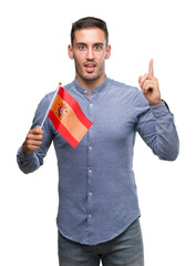 Sticker - Handsome young man holding a flag of Spain surprised with an idea or question pointing finger with happy face, number one