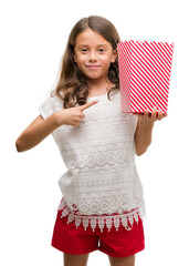 Canvas Print - Brunette hispanic girl eating popcorn very happy pointing with hand and finger