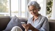 © neirfy - Beautiful happy senior woman with grey hair, using smartphone phone at home