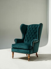 a plush green wing chair with decorative nail heads and solid wood legs.