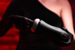 © Granmedia - Sex toys for men. An artificial vagina for masturbation in the hands of a girl in black latex gloves and a black dress on a red background. Sticks two fingers into the toy. Male massager. Sex shop