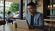 © Gregory Allen Brown - Young asian business man using mobile phone, working on laptop computer at coffee shop. Female freelancer online working, using smartphone surfing the internet, remote work, e-learning