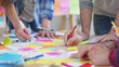 © Plaifah - A group of coworkers brainstorming ideas around a table covered with sticky notes and sketches of graphs, fostering creativity.