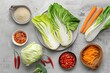 Fresh chinese cabbages and vibrant ingredients prepared for kimchi creation on a grey table