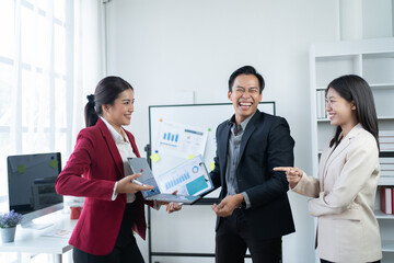 Wall Mural - Group of young business people discussing business while working by using line chart  and laptop in the office together 