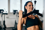Fototapeta Pomosty - Focused girl, working out at the gym, using a machine for her back.