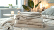Stack of beige clean towels on table in on bed in bedroom with copy space