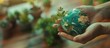 The hands hold a miniature glass Earth on a plant background. Ecology concept. Earth Day.